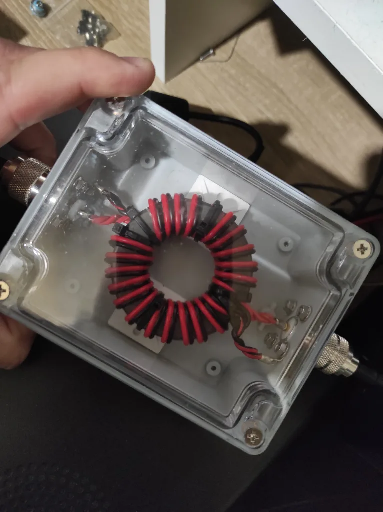 Photo du balun fini, boite PVC transparente avec le tore et les connexions dedans